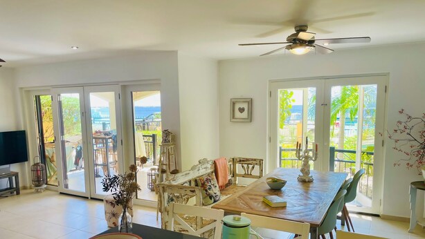 Un comedor amplio con una mesa de madera, sillas y vistas al exterior a través de grandes puertas correderas de vidrio.