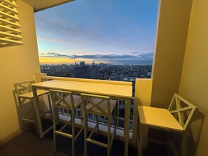 Een balkon met uitzicht op de stad, een witte tafel en twee stoelen.