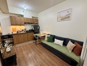 Een gezellige, compacte leefruimte met een kitchenette, een eethoek en een bank.