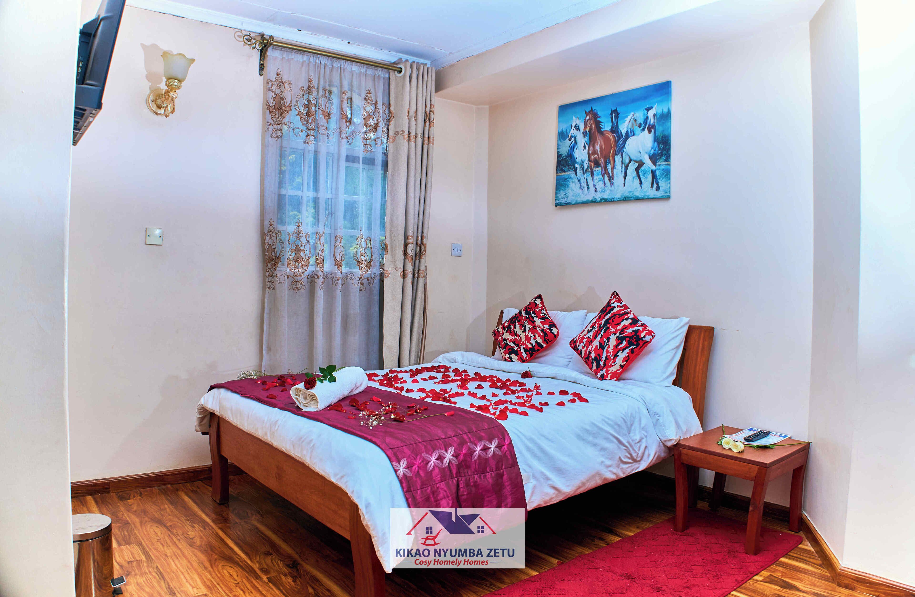 Une chambre à coucher avec un lit en bois, un plaid rouge et un tableau représentant des chevaux accroché au mur.