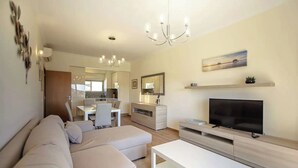 A modern living room with a sofa, TV, and a dining area in the background. - Elegant and cocooning in a luxury residence near the Marina (Albufeira)