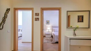 A hallway leading to a bedroom with a bed, bedside table, lamp, and a small decorative item on the wall. - Elegant and cocooning in a luxury residence near the Marina (Albufeira)