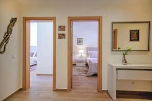 A hallway leading to a bedroom with a bed, bedside table, lamp, and a small decorative item on the wall. - Elegant and cocooning in a luxury residence near the Marina (Albufeira)