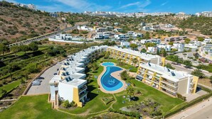 A modern hotel with a central swimming pool, multiple balconies, and a landscaped garden. - Elegant and cocooning in a luxury residence near the Marina (Albufeira)