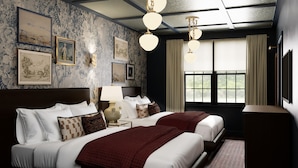 A hotel room with a large bed, two bedside tables, a nightstand, a lamp, a ceiling light fixture, a window with curtains, and framed artwork on the walls. - The Drew Hotel (Plymouth)