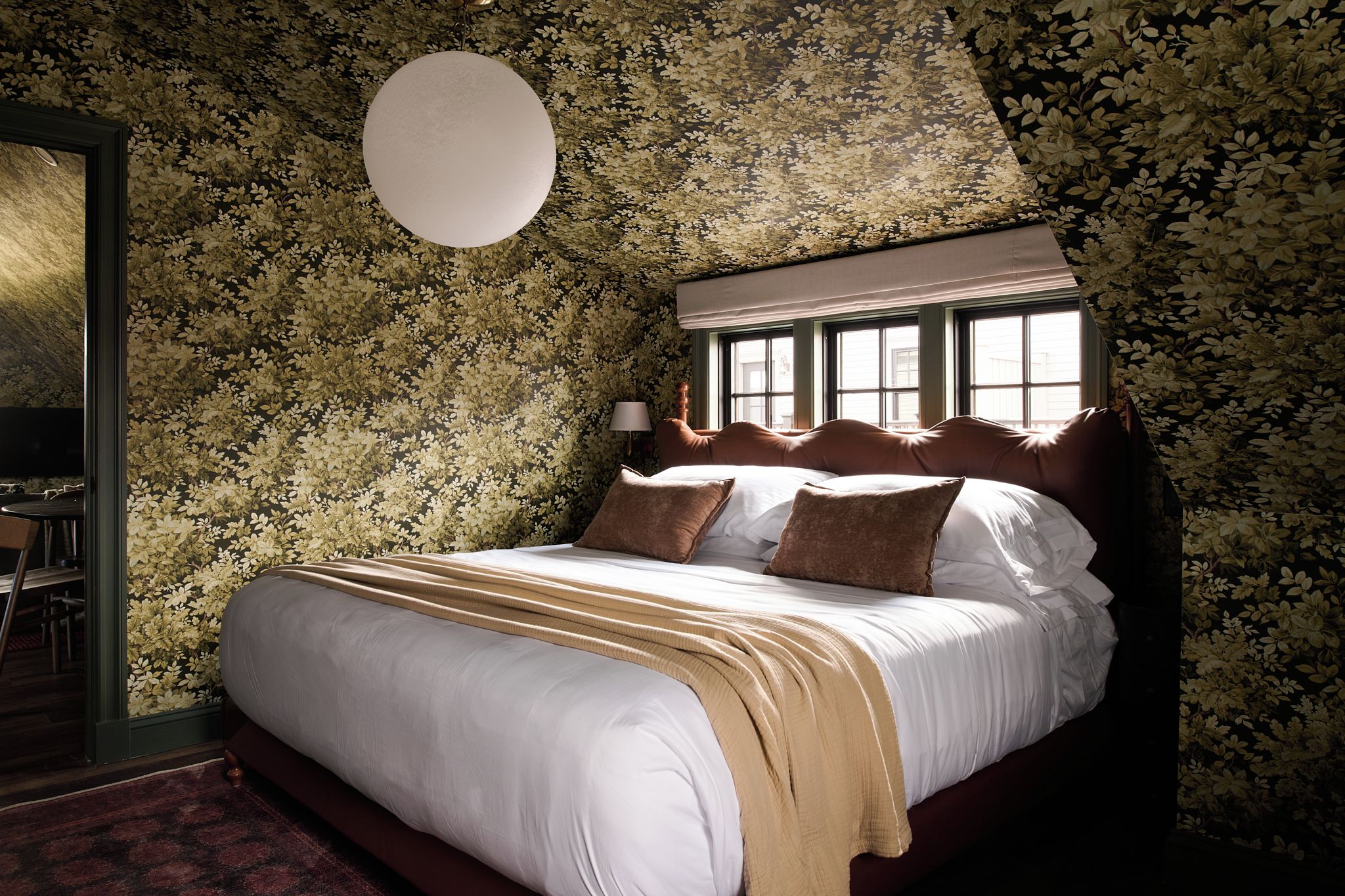 Ein Schlafzimmer mit einem großen Bett, einer runden Lampe und einem Fenster mit vielen Glasscheiben.