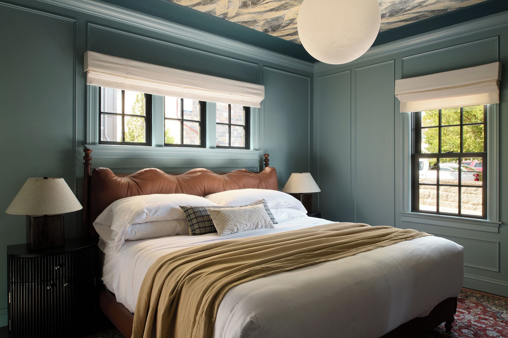 A bedroom with a large bed, two bedside tables, and a ceiling light fixture.