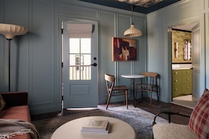 A room with a door, a painting, two chairs, a table, and a sofa. - The Drew Hotel (Plymouth)