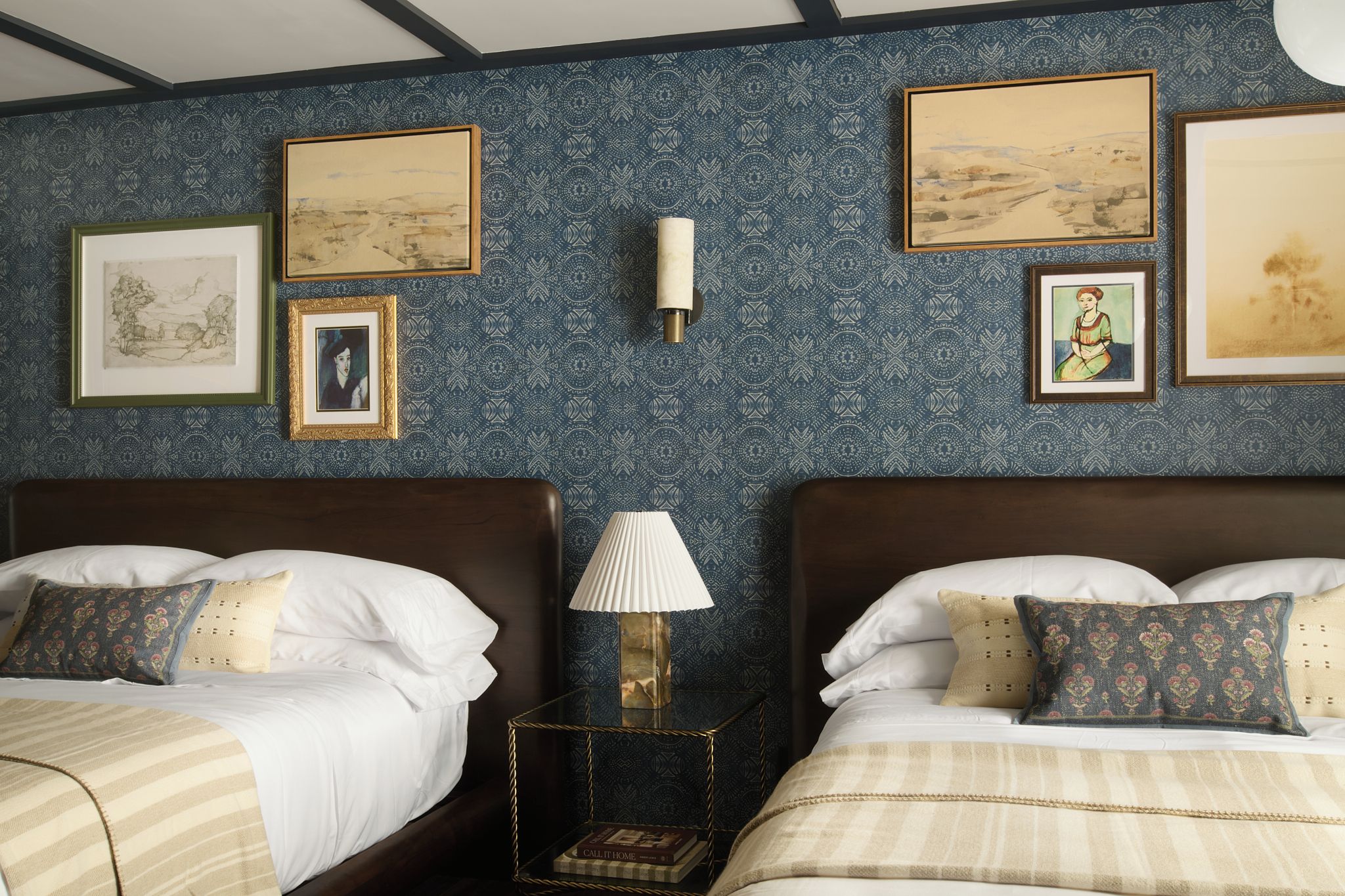 Habitación de hotel con dos camas, una mesita de noche y un cuadro decorativo en la pared.