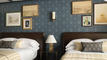 Habitación de hotel con dos camas, una mesita de noche y un cuadro decorativo en la pared.