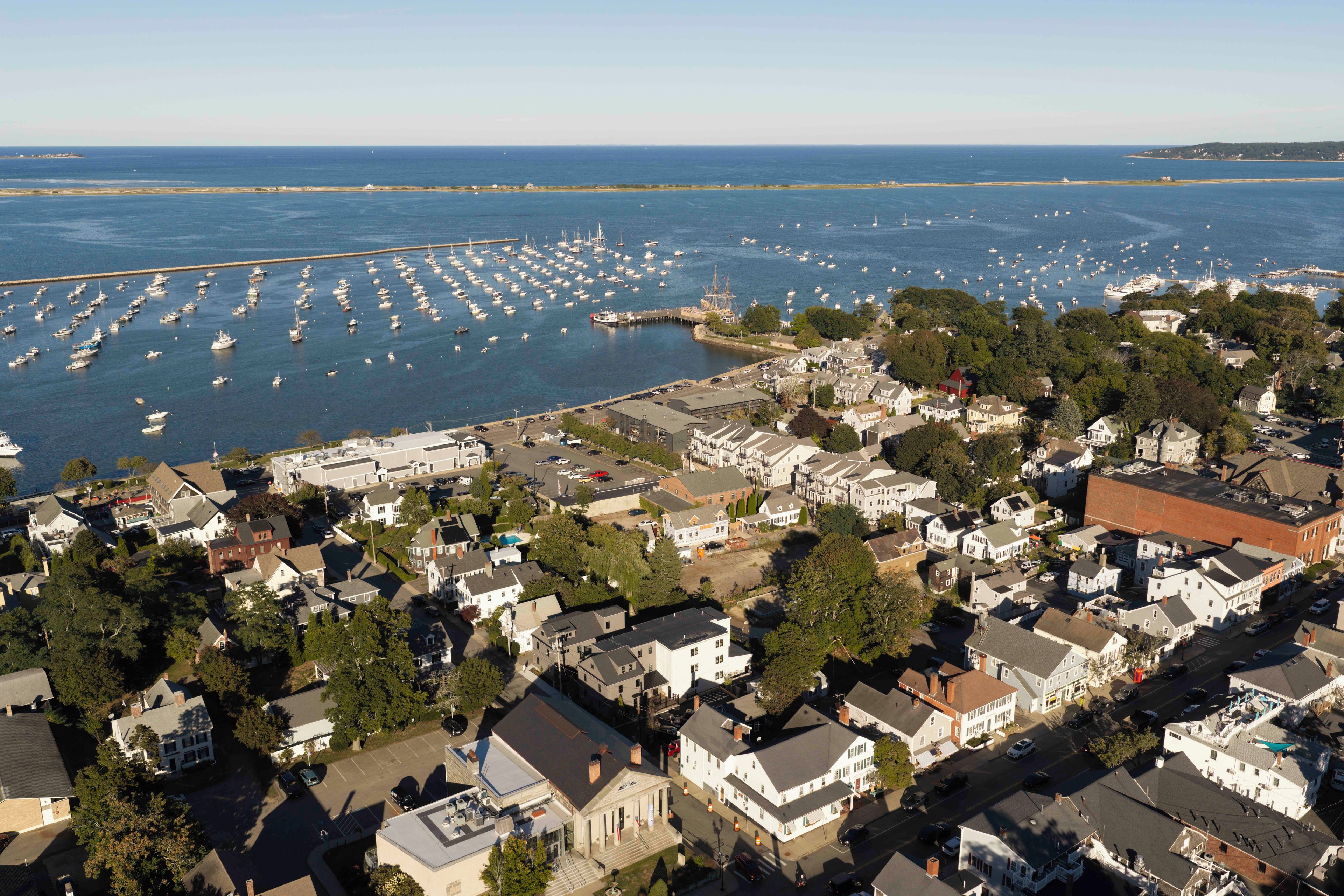 A coastal town with a marina filled with boats, surrounded by residential buildings and a prominent church.