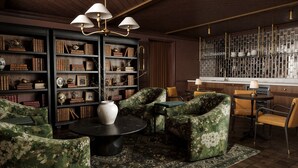 A library with bookshelves, a vase, and a table with chairs. - The Drew Hotel (Plymouth)