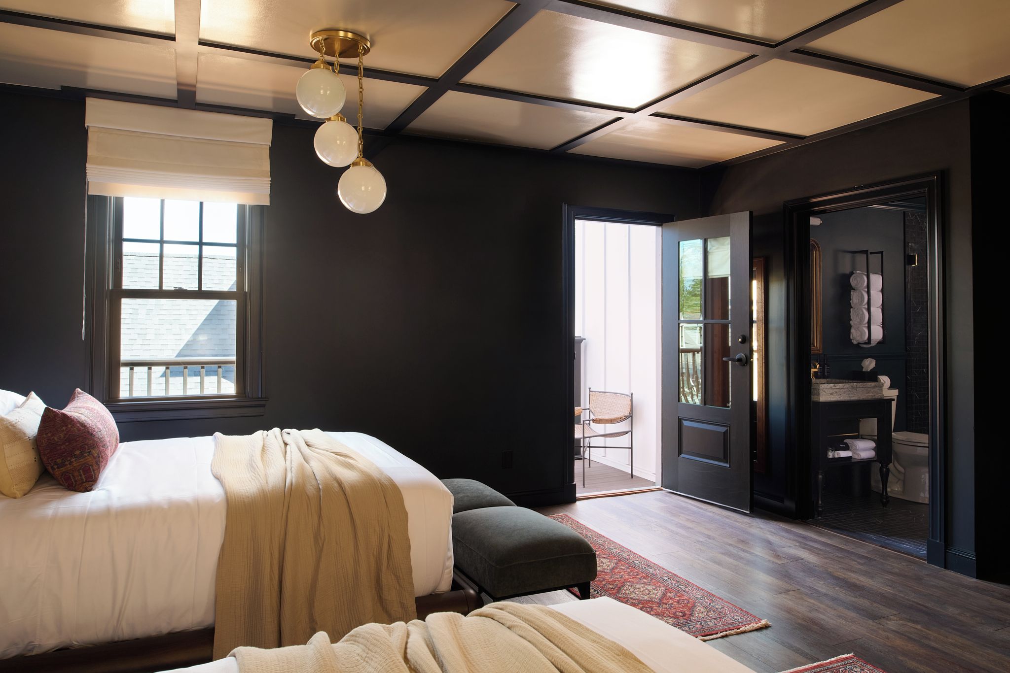 A modern bedroom with a large bed, a walk-in closet, and a view of the outdoors.