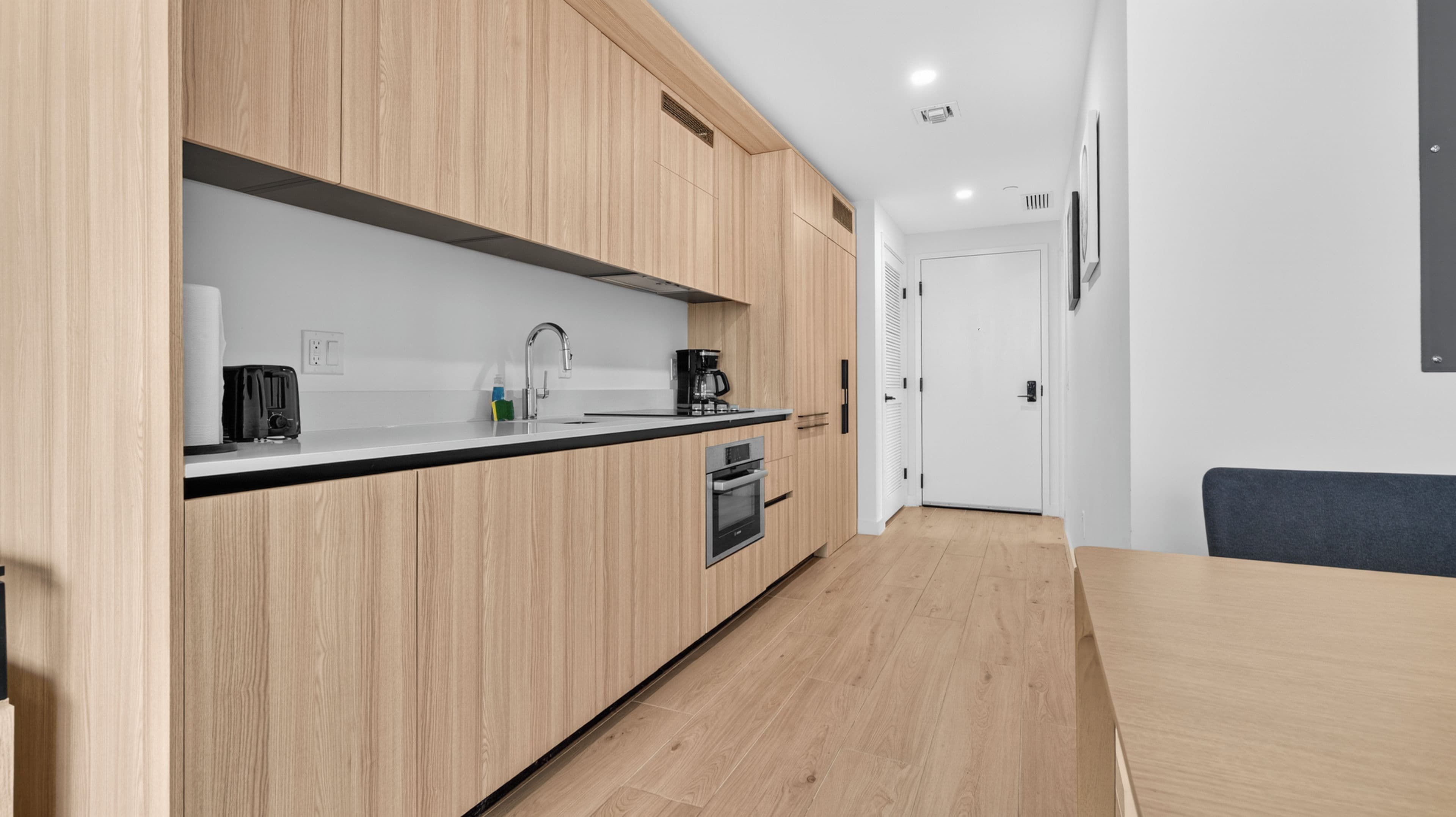 Een moderne keuken met houten kastjes, een zwart aanrecht en een inbouwoven.