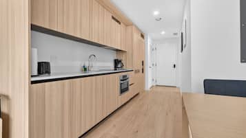 Een moderne keuken met houten kastjes, een zwart aanrecht en een inbouwoven.