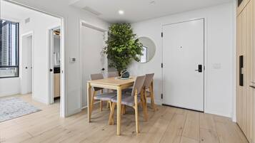 Un intérieur moderne avec une table à manger en bois, des chaises, une plante en pot et un miroir rond accroché au mur.