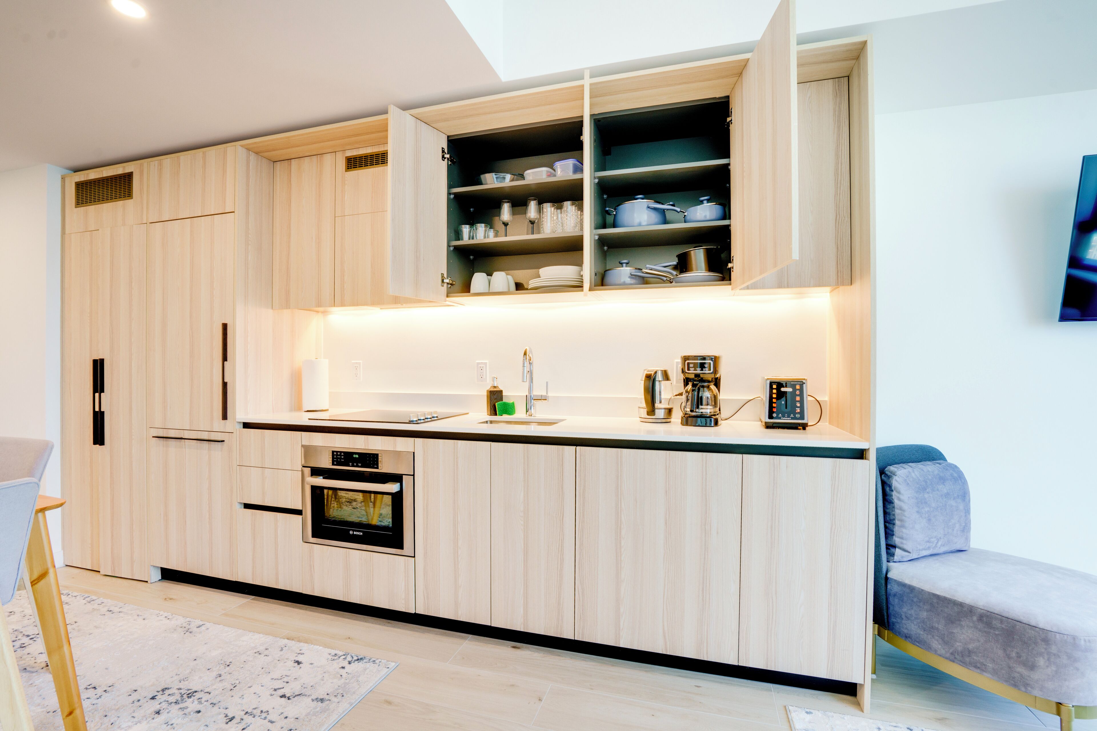 A modern kitchen with built-in appliances, a dining area with a bench, and a large window.