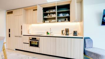 A modern kitchen with built-in appliances, a dining area with a bench, and a large window.