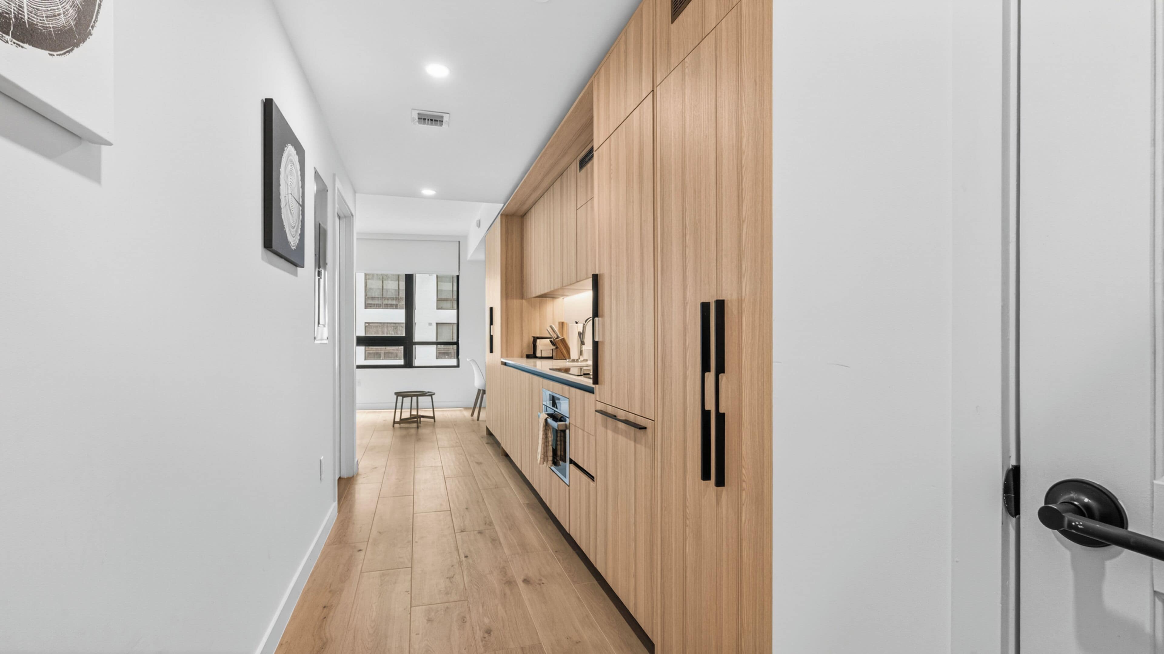 A modern kitchen with wooden cabinets, a refrigerator, and a window.