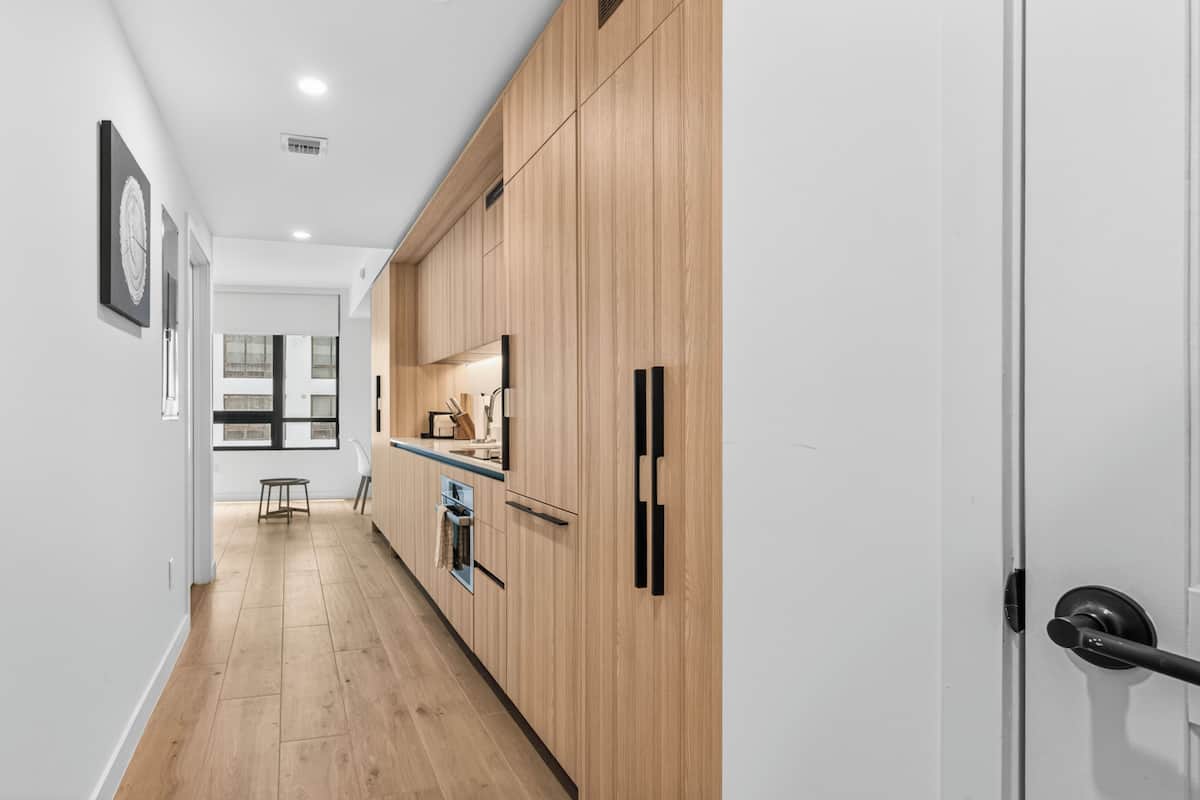 A modern kitchen with wooden cabinets, a refrigerator, and a window.