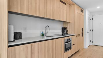 Eine moderne Küche mit Holzschränken, einer Edelstahl-Spüle, einer Kaffeemaschine, einem Toaster und einem Backofen.