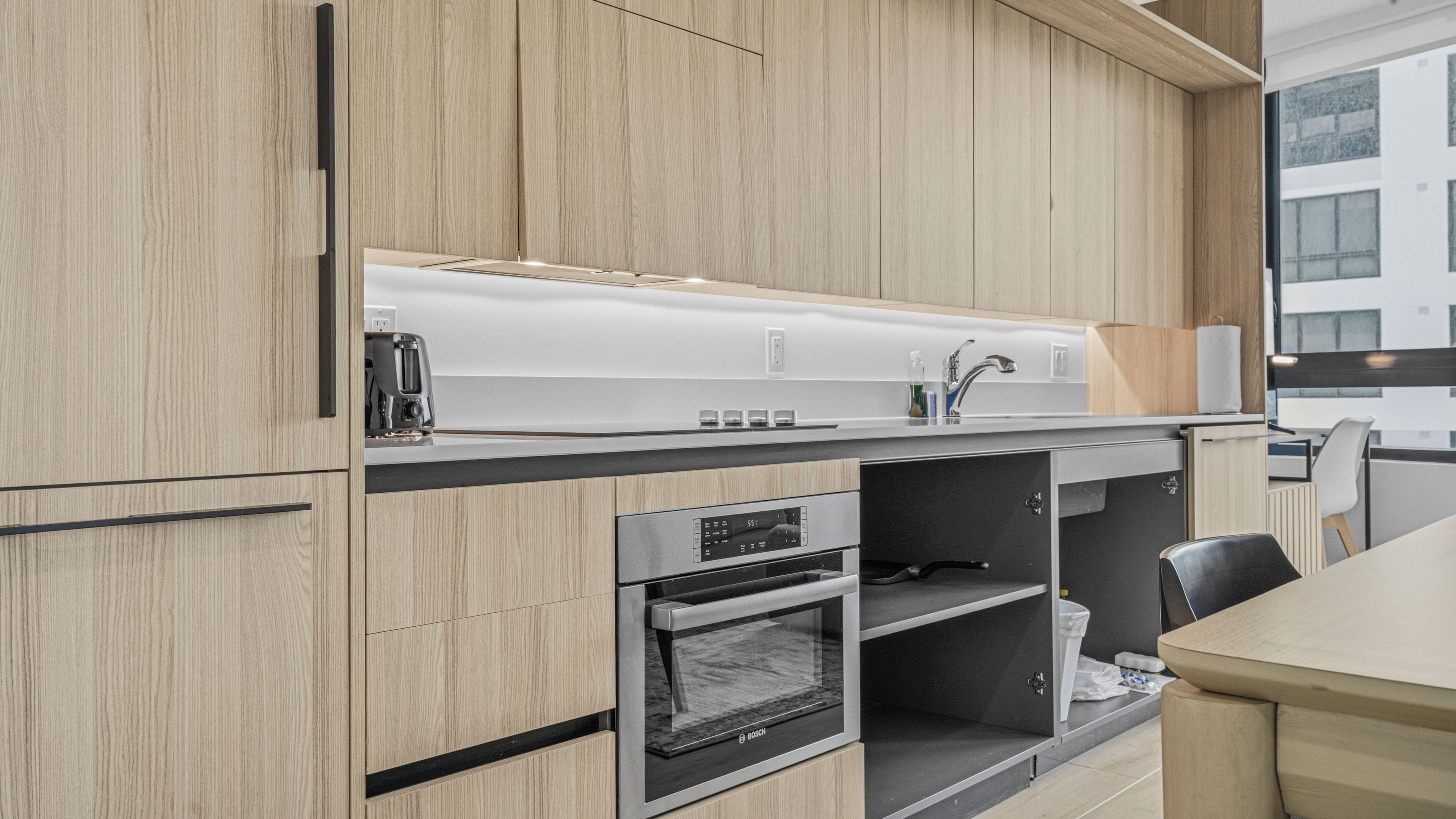Eine moderne Küche mit Holzausstattung, einem Backofen und einer Edelstahl-Dunstabzugshaube.