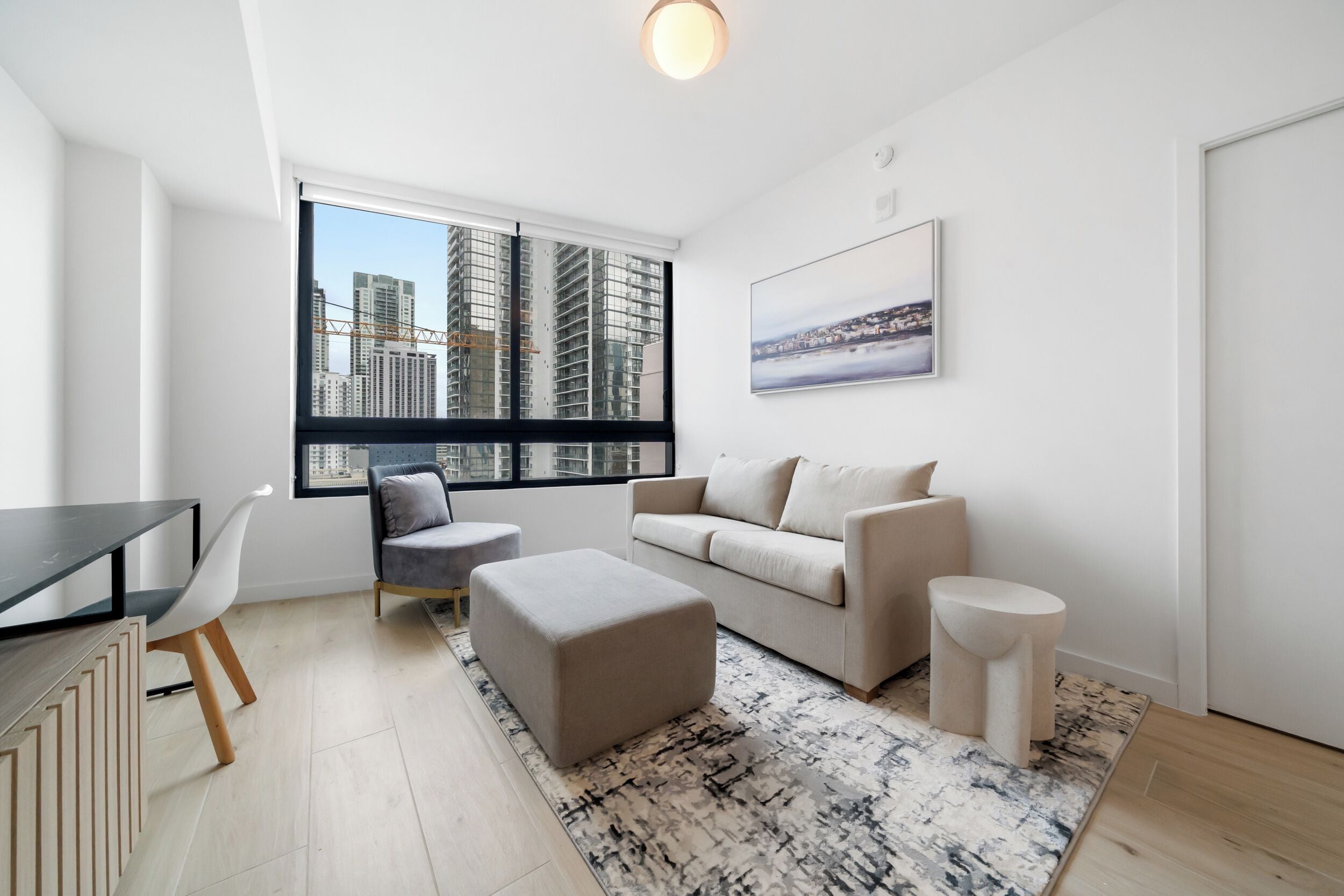 Una sala de estar moderna con un sofá, un reposapiés, un sillón y una mesa de comedor.