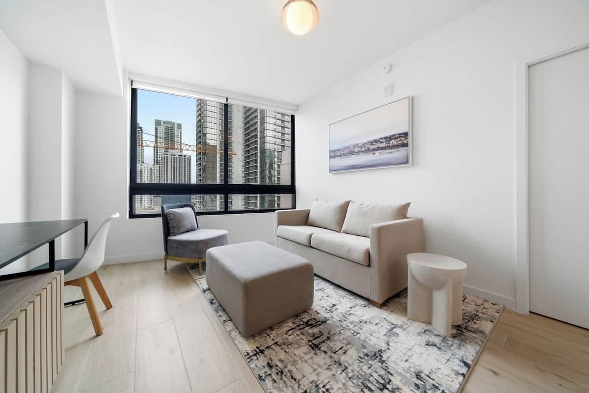 Una sala de estar moderna con un sofá, un reposapiés, un sillón y una mesa de comedor.