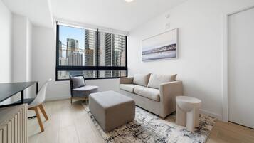 A modern living room with a sofa, ottoman, chair, and a dining table.