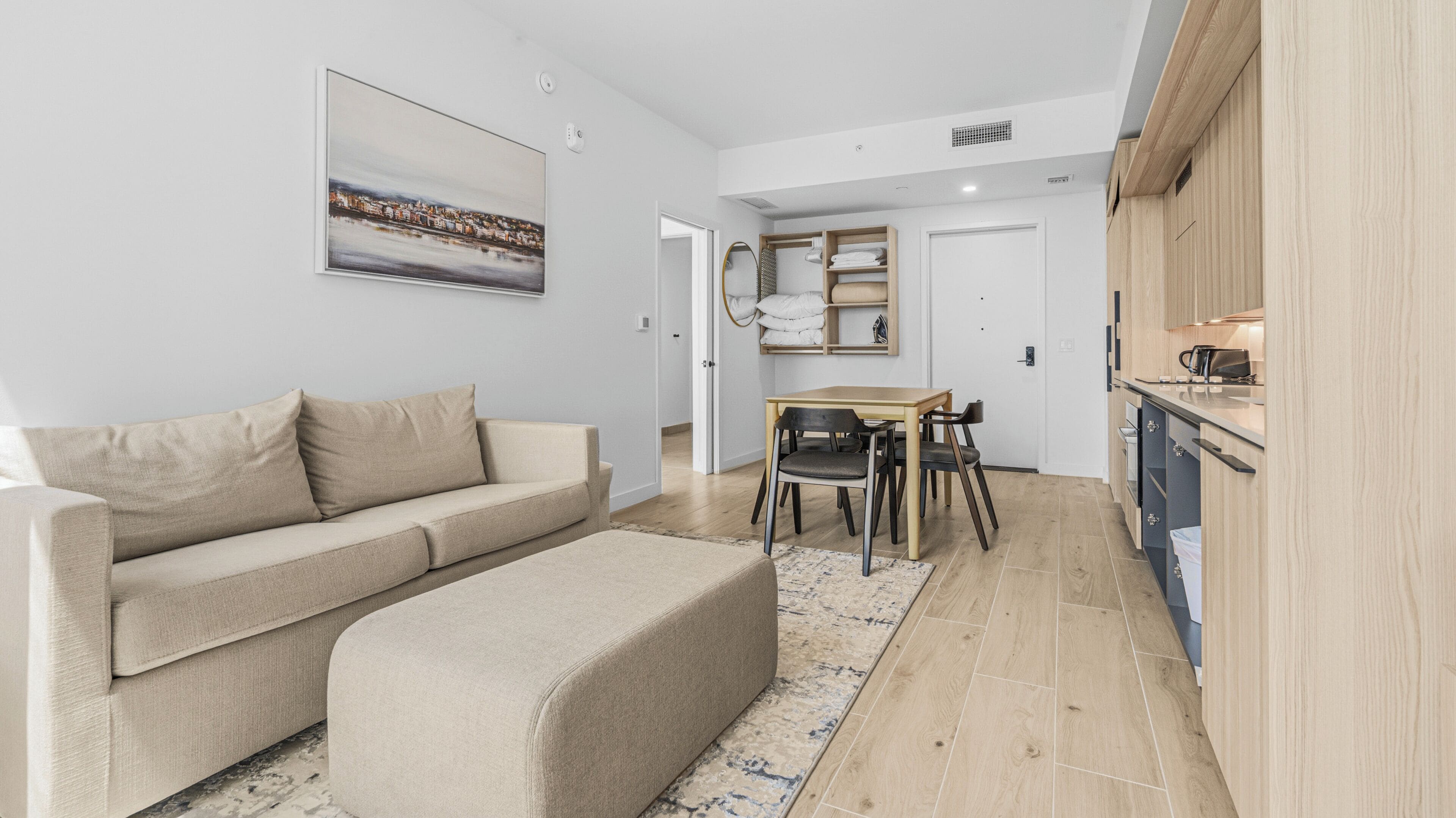 Ein modernes Wohnzimmer mit einer Couch, einem Hocker und einem Essbereich mit Tisch und Stühlen.