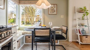 A kitchen with a dining table, chairs, a hanging light fixture, and a view of the outdoors. - The Ballard Vista | Sleeps 6 + Patio & Fire Pit (Seattle)