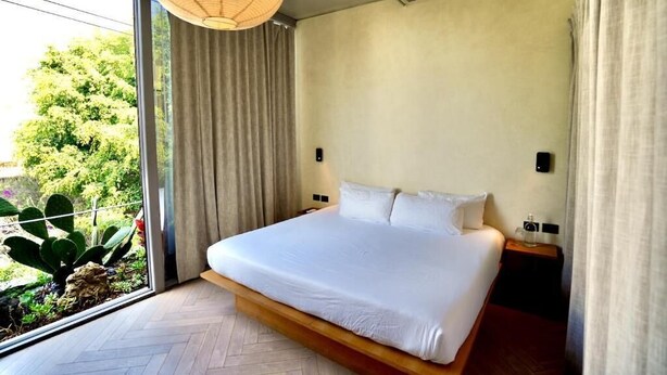 Ein modernes Schlafzimmer mit einem großen Bett, einem Fenster mit Vorhängen und einer Hängeleuchte.