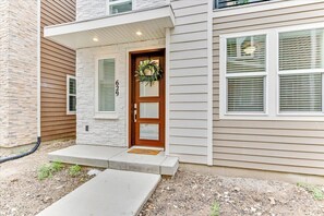 A modern two-story house with a stone facade, a wooden door with a wreath, and a number '629' above the door.