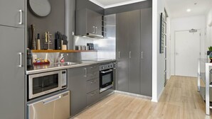 A modern kitchen with grey cabinets, stainless steel appliances, and a wooden countertop.