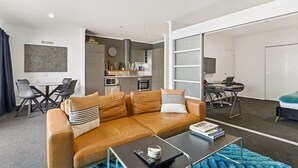 A modern living room with a brown leather sofa, a coffee table, and a blue rug.