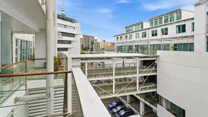 A modern building with multiple floors, a covered walkway, and a parking area with cars.