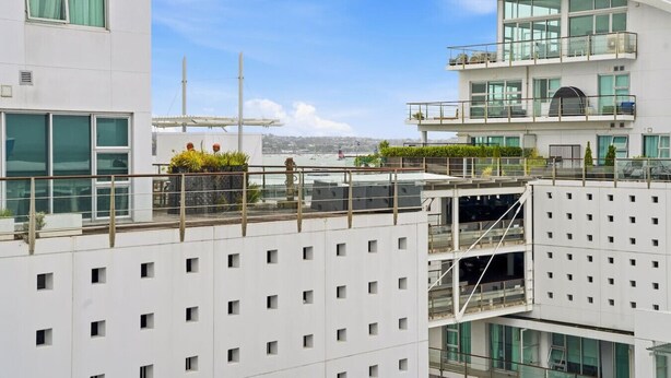 A modern building with multiple floors, large windows, and a rooftop garden.