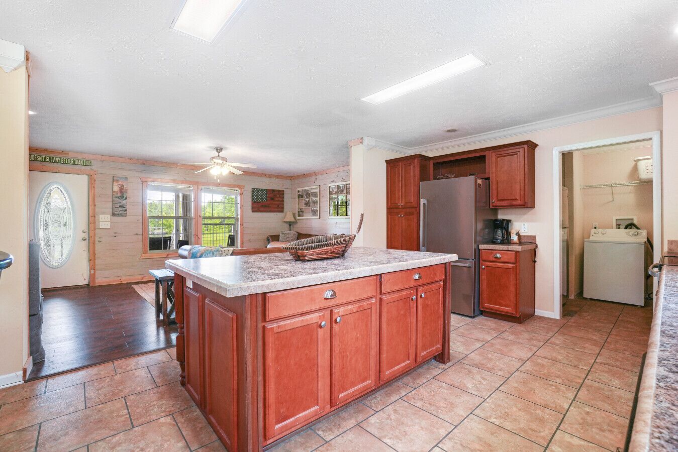 A spacious kitchen with a large island, wooden cabinets, and a refrigerator.