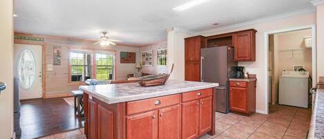 A spacious kitchen with a large island, wooden cabinets, and a refrigerator.