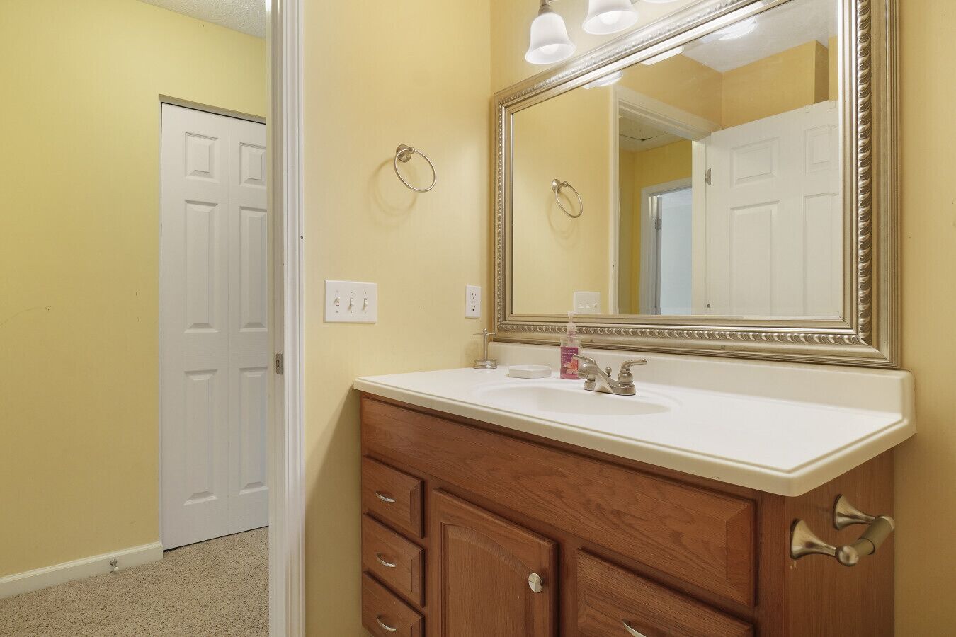 A bathroom with a wooden vanity, a large mirror, and a white sink.