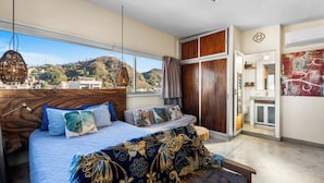 Een slaapkamer met een groot bed, uitzicht op de stad en een balkon.