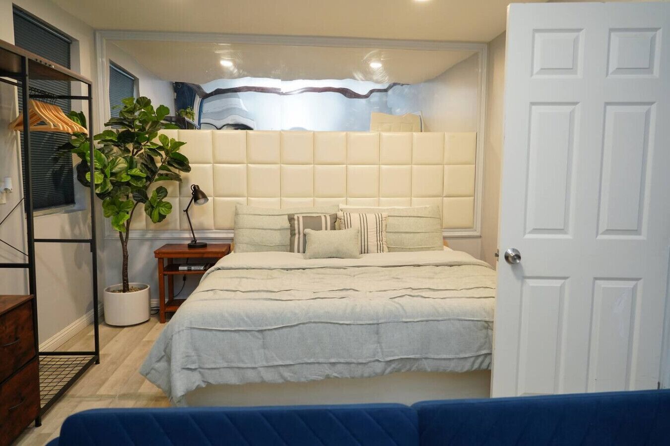Une chambre à coucher comprenant un lit, une table de chevet, une lampe, une plante en pot et une armoire.