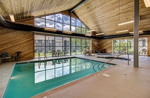 En inomhuspool med väggar av trä och stora fönster.