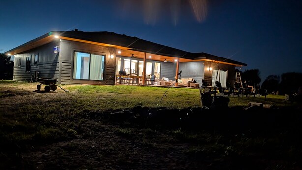 Eine zweistöckige Blockhütte mit überdachter Veranda und Sitzgelegenheit im Freien.