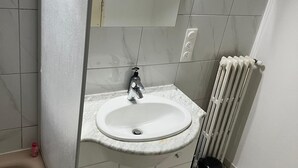 A bathroom with a white sink, a mirror, and a radiator.