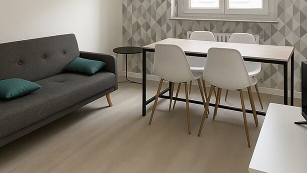 A modern living room with a grey sofa, a dining table with four chairs, and a large window with a view of buildings.