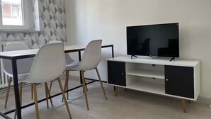A modern room with a white desk, a flat-screen TV, and two white chairs.