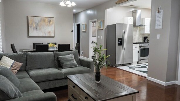 Een moderne woonkamer met een grijze bank, een salontafel en een keuken op de achtergrond.