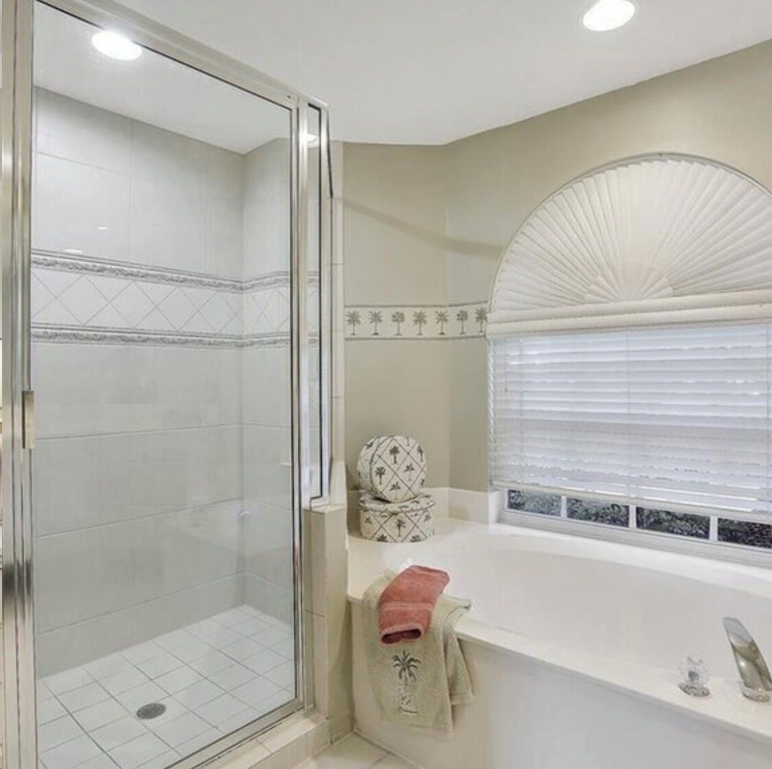 Un baño con cabina de ducha de vidrio, una bañera blanca y una ventana con persianas.