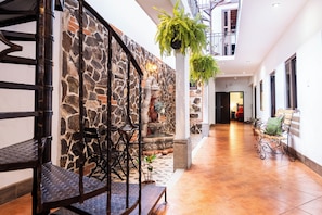 A spacious indoor area with a stone wall, a staircase, and a bench. - Los Faroles Hotel & Spa (Antigua Guatemala)